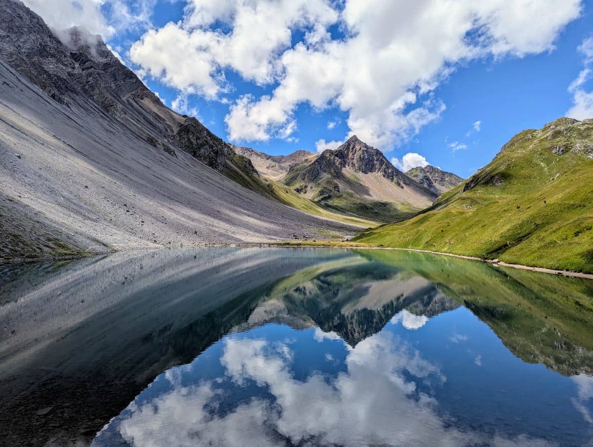 Wolken und Berge spiegeln sich malerisch im tiefblauen Wasser des Älpisee, einem der schönsten Bergseen der Schweiz.