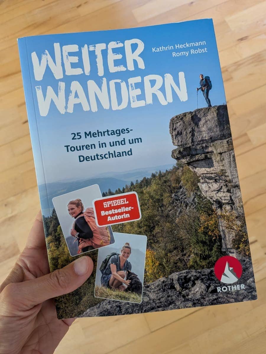 Linda hält das perfekte Geschenk für Wanderer in der Hand: ein Buch mit 25 Weitwanderwegen in Deutschland.