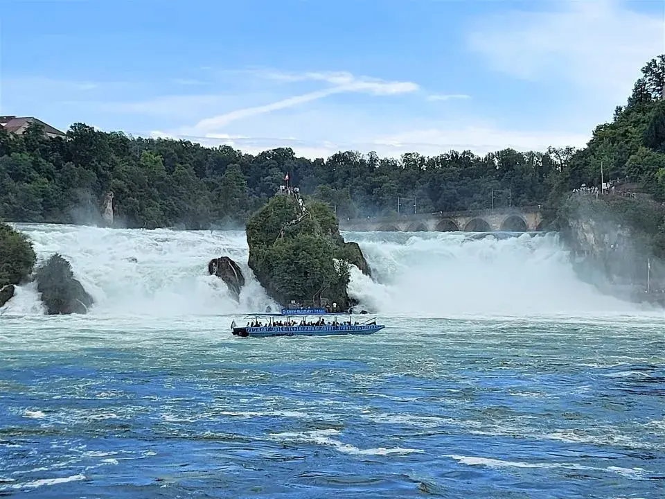 Blick auf den Rheinfall mit seinem Mittelfelsen und den Ausflugsbooten sowie Schloss Laufen