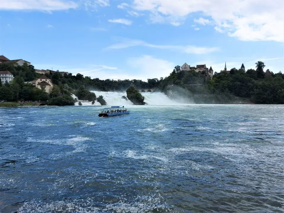 Blick auf den Rheinfall mit seinem Mittelfelsen und den Ausflugsbooten sowie Schloss Laufen