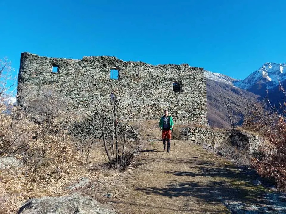 Jan entfernt sich wandernd von der Ruine des Castello di Challant im Hintergrund, oberhalb des Val d'Ayas.