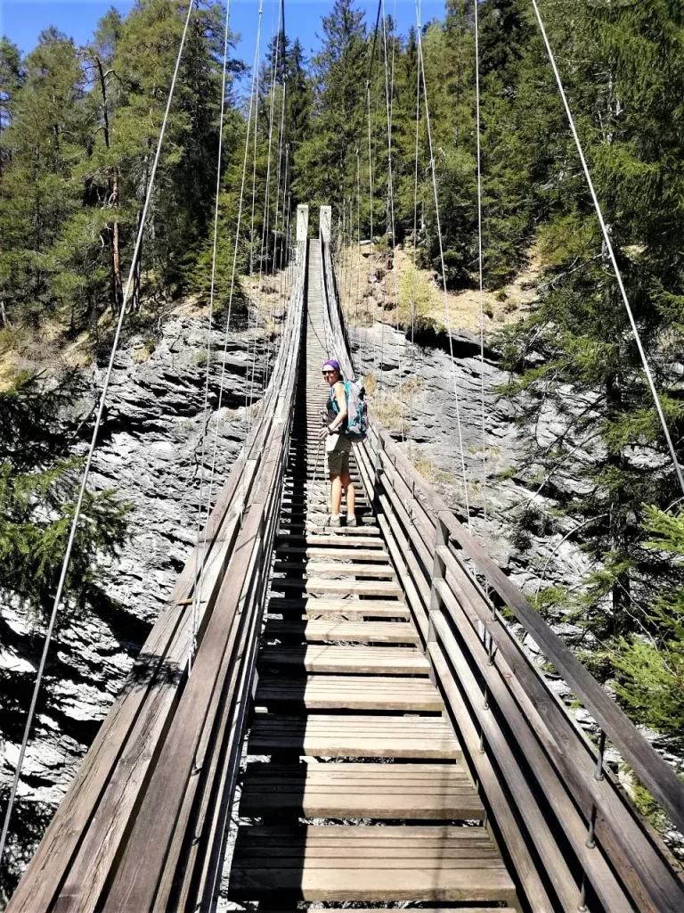 Linda steht auf der hölzernen Hängebrücke Traversinasteg in der Viamala Schlucht, auf dem Wanderweg nach Thusis