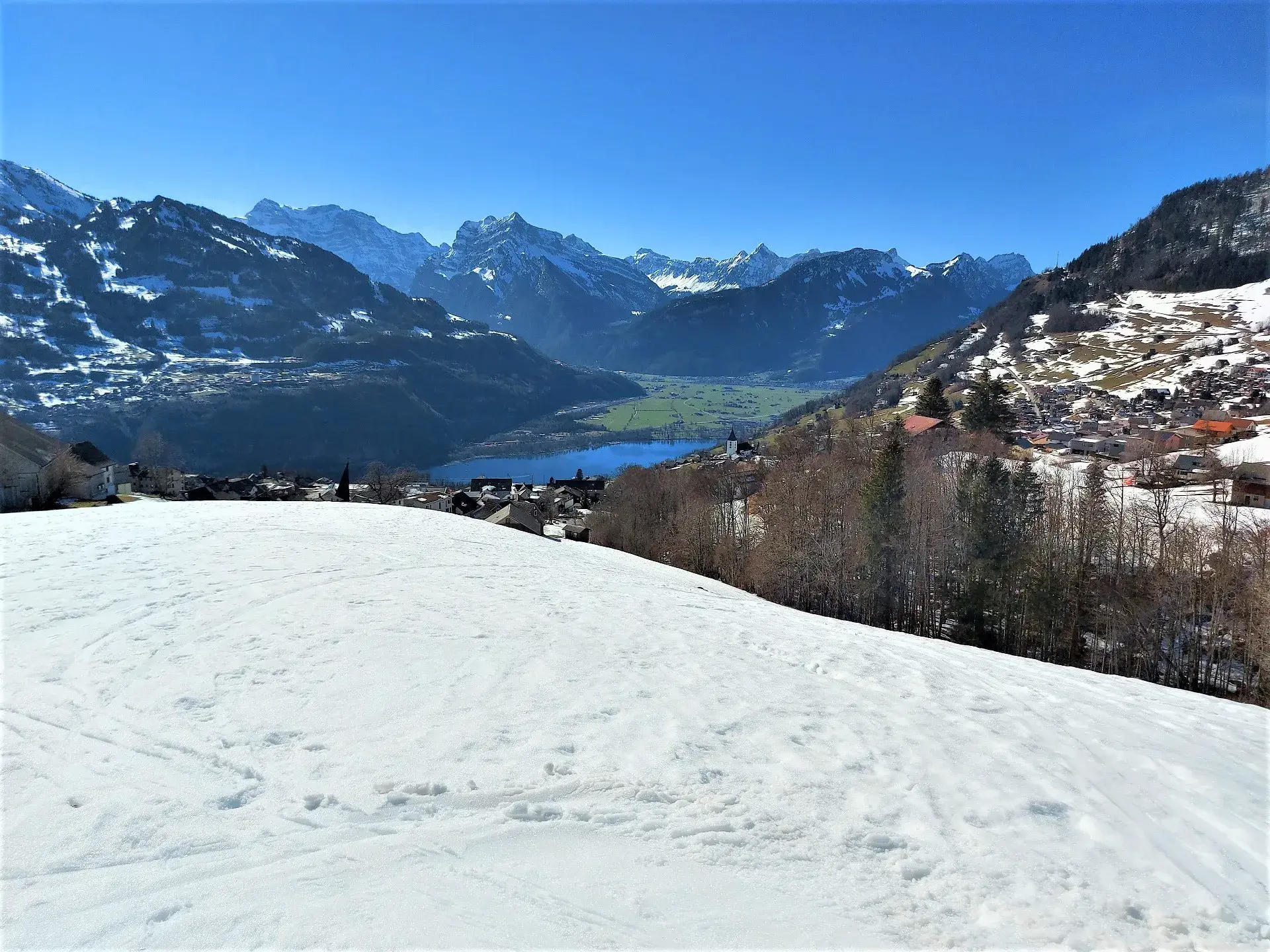 Blick auf das verschneite Amden und den blauen Walensee, beim Schneeschuhwandern Schweiz