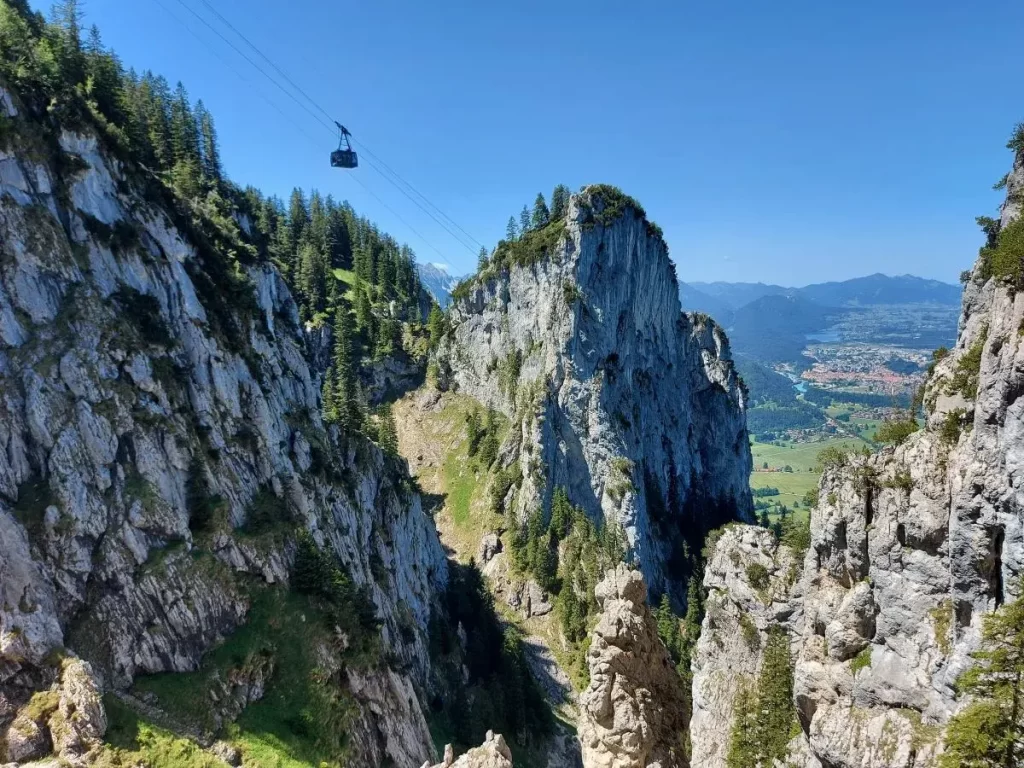 Die Gondel der Tegelbergbahn passiert steile Felsen mit tollen Blicken auf Füssen im Hintergrund.