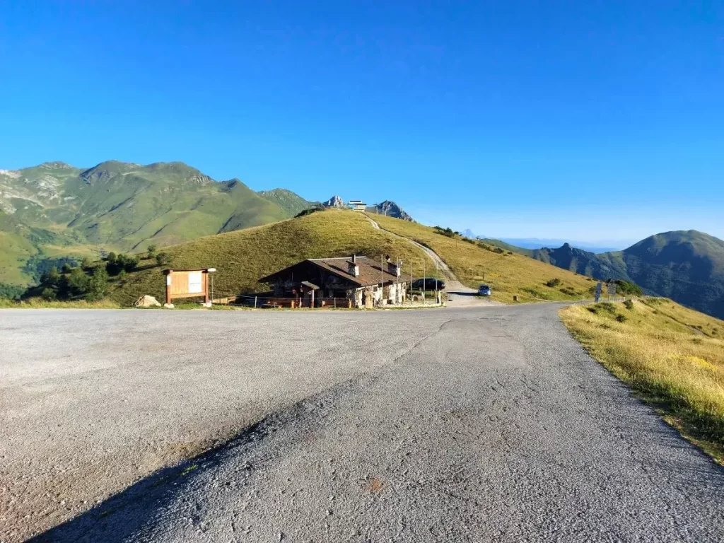 Das Chalet Marmotte liegt malerisch unterhalb des Colle di Tenda, umgeben von sanften Hügeln und einer ruhigen Berglandschaft. Die asphaltierte Straße im Vordergrund führt zu diesem beliebten Rastpunkt.