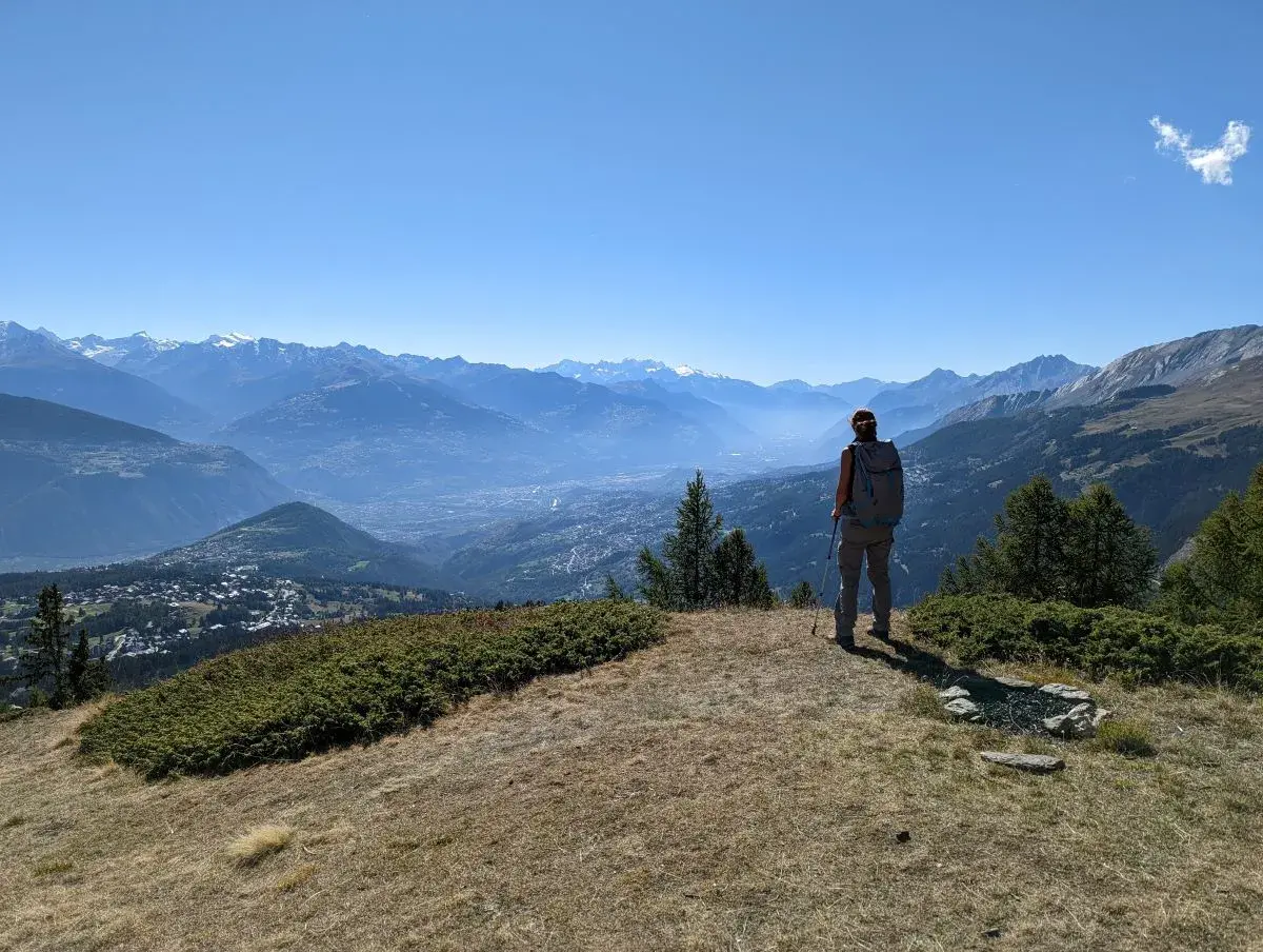 Linda geniesst den Ausblick auf das Rhonetal und die unzähligen Alpengipfel von einem Aussichtspunkt oberhalb von Crans Montana