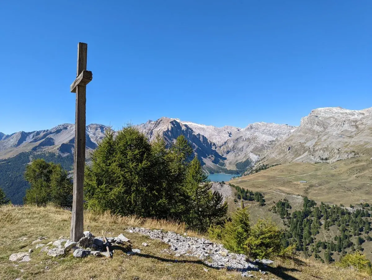 Gipfelkreuz am Cry d'Er mit Stausee und Alpen im Hntergrund