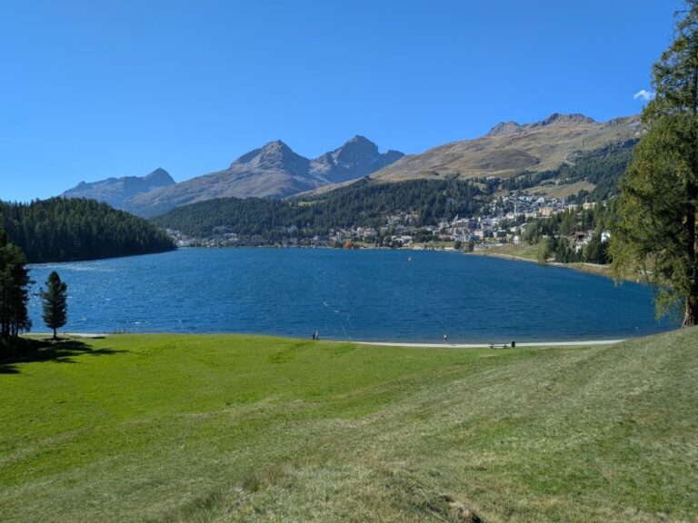 Blick über den in der Sonne leuchtenden St. Moritzsee auf die Stadt St. Moritz, einem beliebten Kurort in Graubünden.