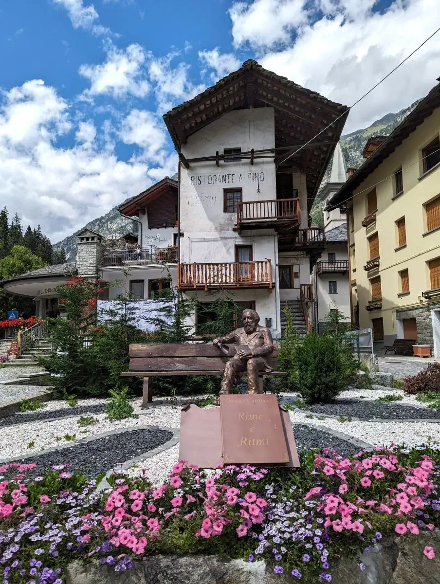 Statue und Blumen am Dorfeingang von Gaby im Valle del Lys