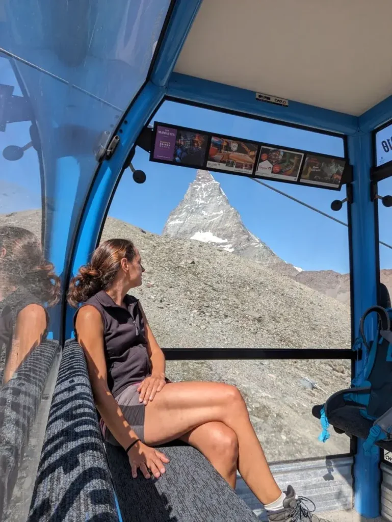 Linda sitzt in der Seilbahn und blickt auf das Matterhorn, das majestätisch vor der Gondel aufragt. Diese Perspektive zeigt eindrucksvoll die Nähe des Aostatals zu einem der berühmtesten Berge der Alpen.