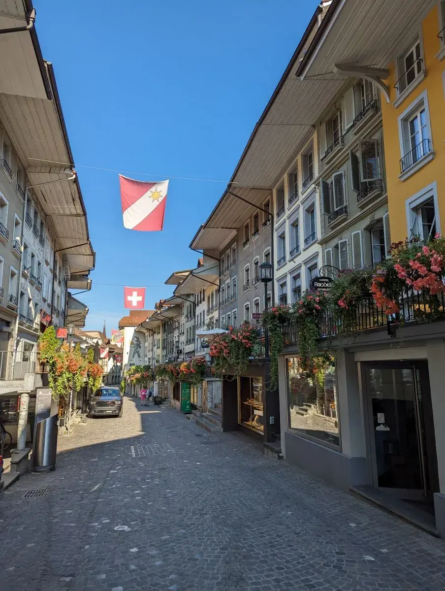 Obere Hauptgasse der Stadt Thun: Kopfsteinpflaster, hohe, bunte Stadthäuser und alles mit Blumen verziert