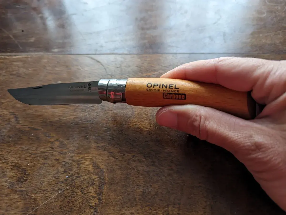 Linda hält das Opinel Messer, das perfekte Geschenk für Naturliebhaber, in der hand