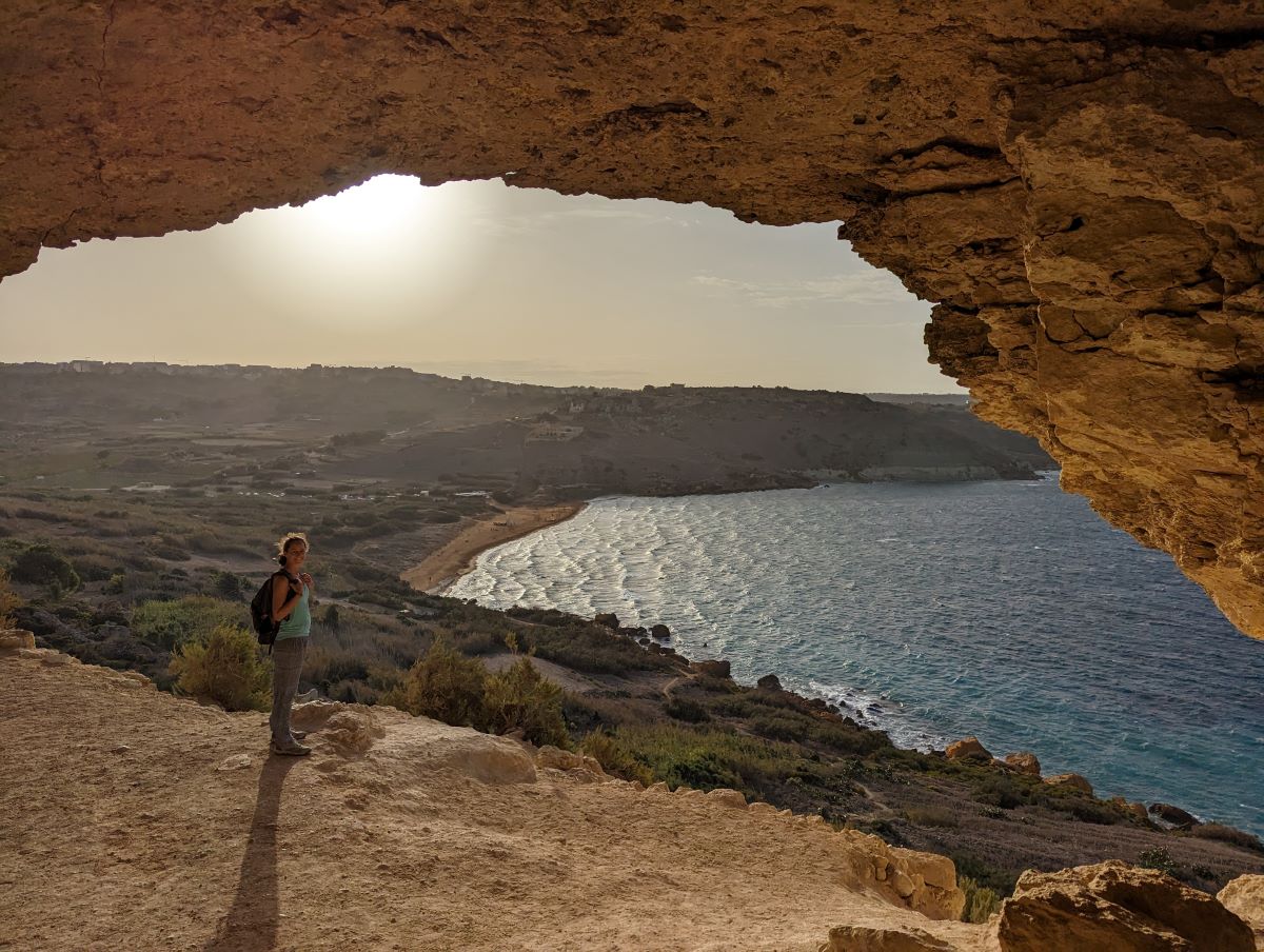 Linda steht in der Tal-Mixta-Höhle mit Blick auf den breiten Sandstrand der Ramla Bay, einem Highlight des Gozo Coastal Walk.