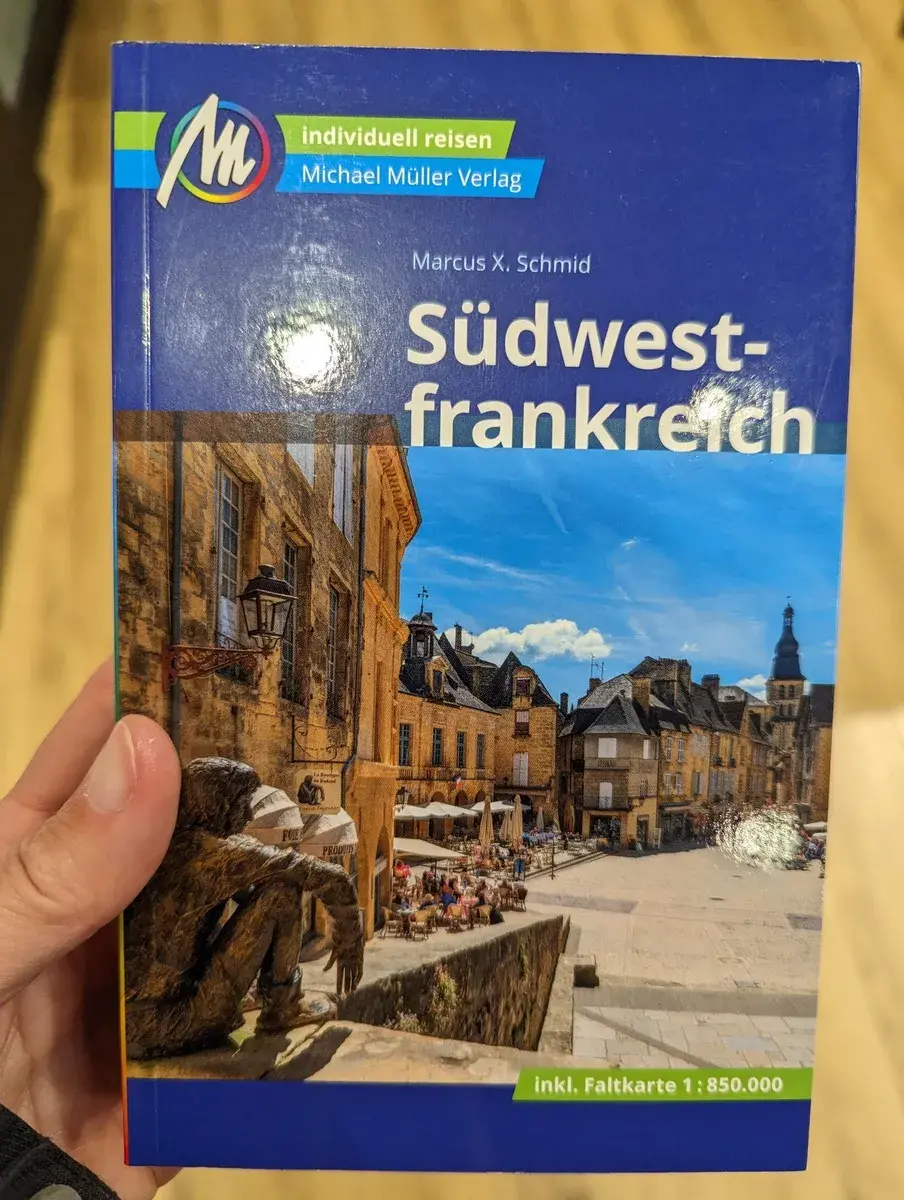 Linda hält den Reiseführer über Südwest Frankreich in der Hand
