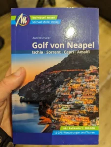 Linda hält den Reiseführer vom Golf von Neapel in der Hand