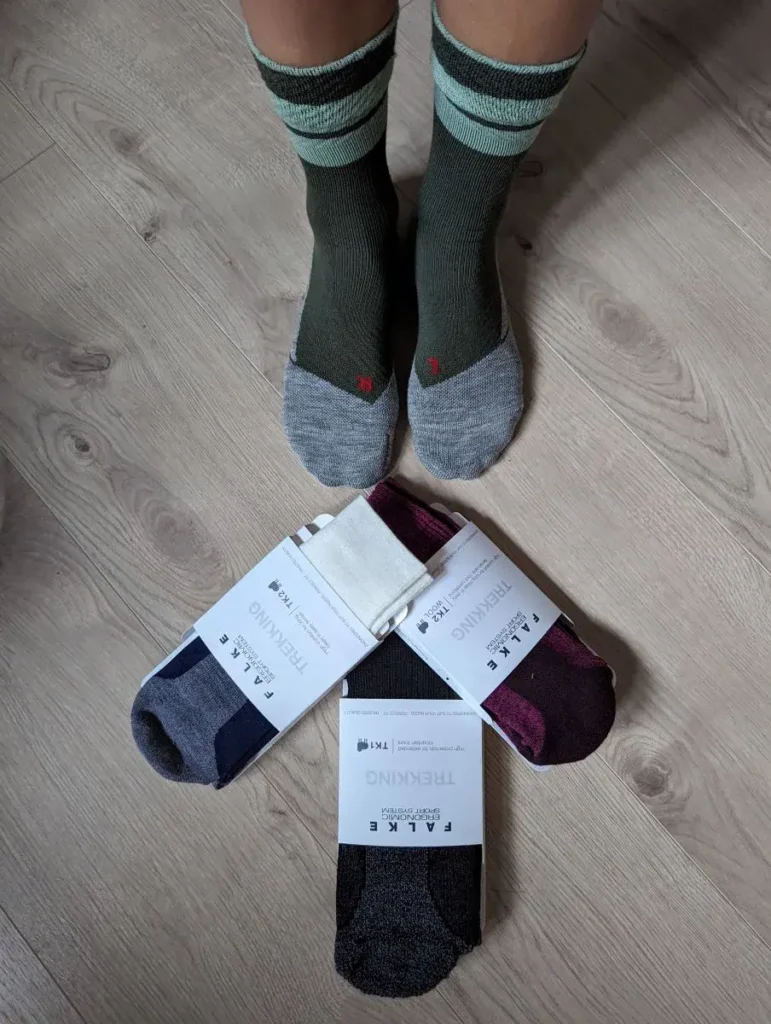 Linda guckt auf ihre Beine und Füße an denen sie bunte Falke Wandersocken trägt