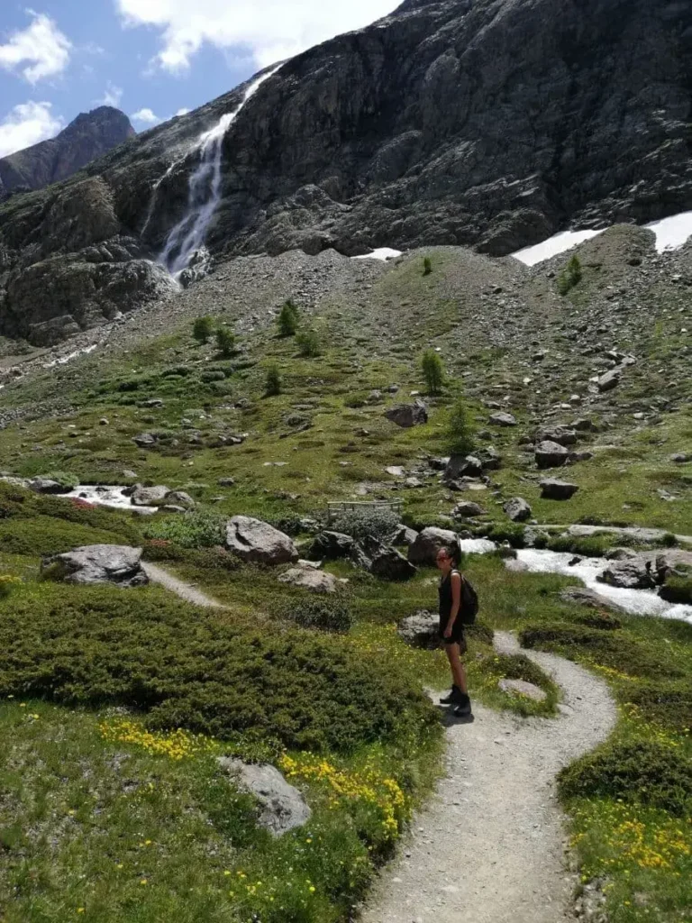 Linda steht auf einem Wanderweg im Martelltal, vor einem Gletscherwasserfall 