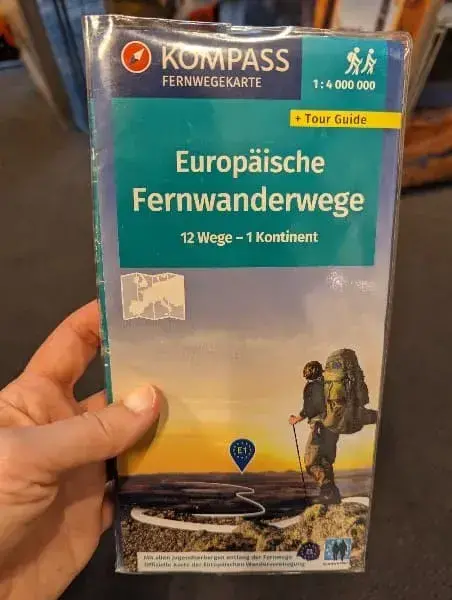Linda hält die Kompass Wanderkarte über Fernwanderwege in Europa in der Hand