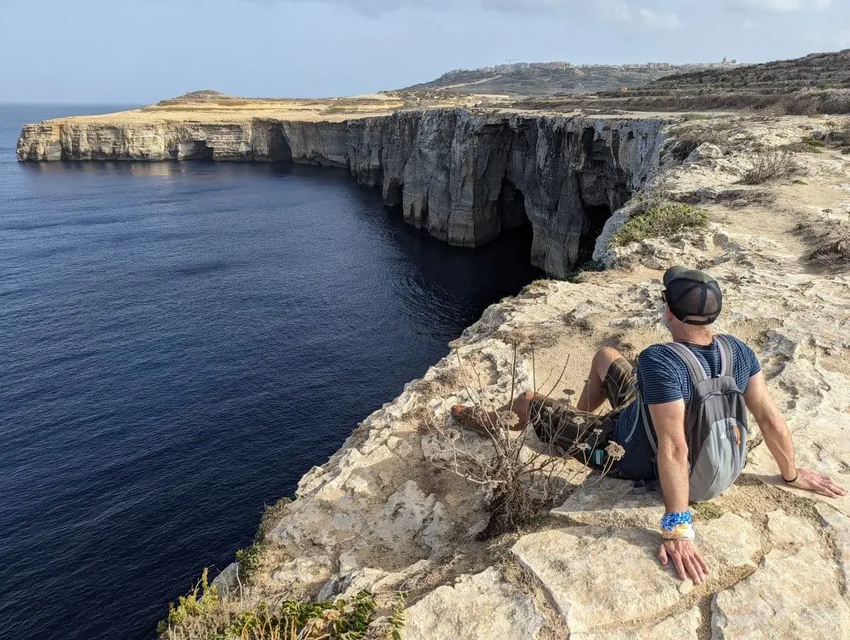 Linda geniesst die Aussicht von den steilen Felsklippen auf das Mittelmeer auf dem Gozo Coastal Walk.