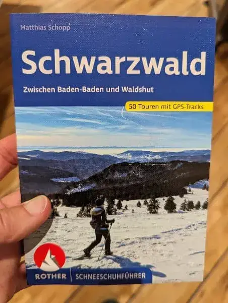 Linda hält ein Buch mit Winterwanderungen im Schwarzwald in der Hand