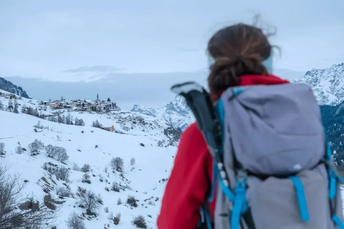 Linda guckt von der winterlichen Via Engiadina auf das Bergdorf Guarda