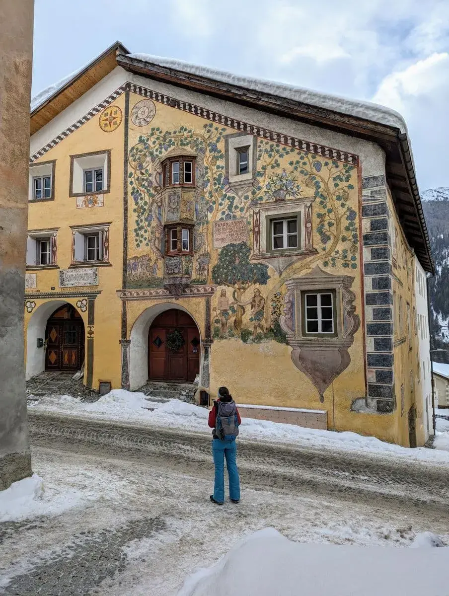 Linda bewundert eine gelbe und schön verzierte Engadinerhaus in Ardez