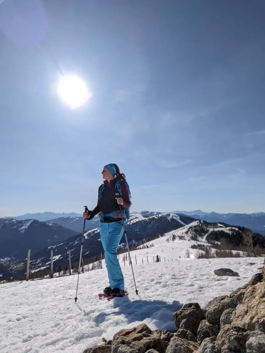 Linda geniesst die Aussicht auf verschneite Berge bei strahlendem Sonnenschein, beim Winterwandern von der Brunnachhöhe