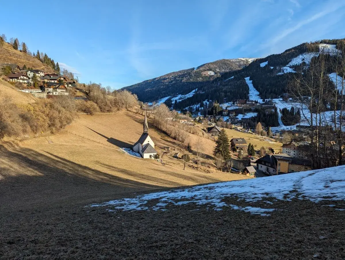 St.-Kathrein-Kirche auf dem Sonnenhang der Kirchheimer Talrunde. Die verschneiten Nockberge im Hintergrund