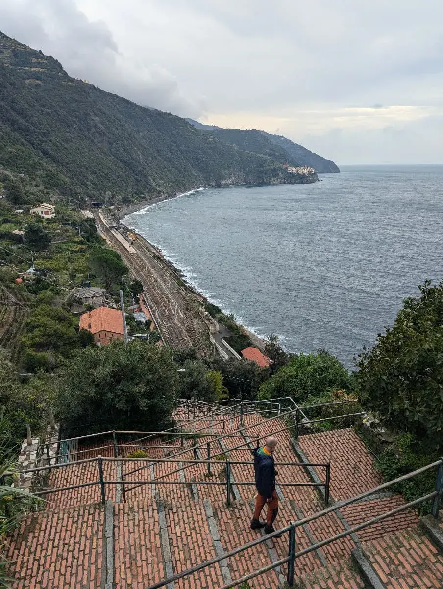 Eine steile Treppe aus Ziegelsteinen führt zum Bahnhof von Corniglia hinab, der direkt an der Küste liegt. Die eindrucksvolle Szenerie entlang der Treppen zeigt die charakteristische Küstenlinie der Cinque Terre.