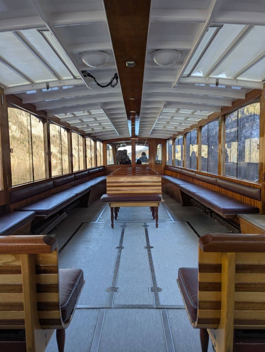 Das helle Innere eines traditionellen Ausflugsschiffs auf dem Königssee mit Holzdetails und langen Sitzbänken, die auf den Winterausflug abgestimmt sind.
