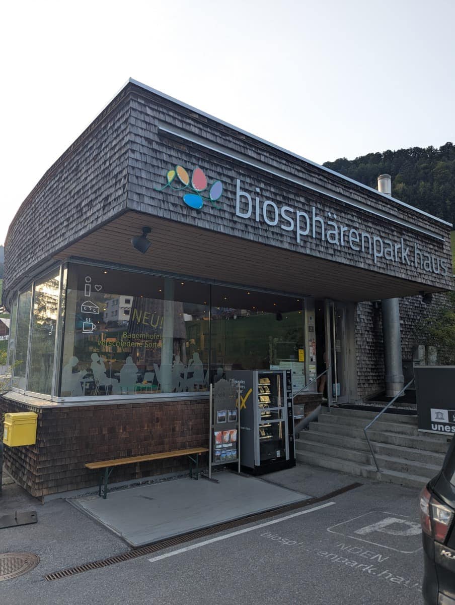 Das Besucherzentrum „biosphärenpark.haus“ in Sonntag zeigt eine moderne Holz-Glas-Fassade mit Vendingautomaten und gelber Postbox. Es ist eine gute Anlaufstelle für Informationen und regionale Produkte aus dem Großen Walsertal.