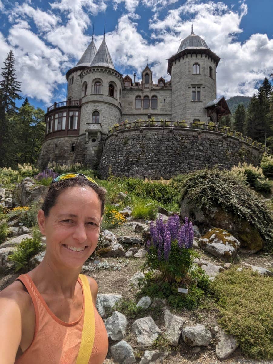 Linda lächelt vor dem märchenhaften Schloss Savoia in Gressoney. Das Schloss ist eine der bekanntesten Sehenswürdigkeiten im Aostatal und lockt mit alpinem Charme.