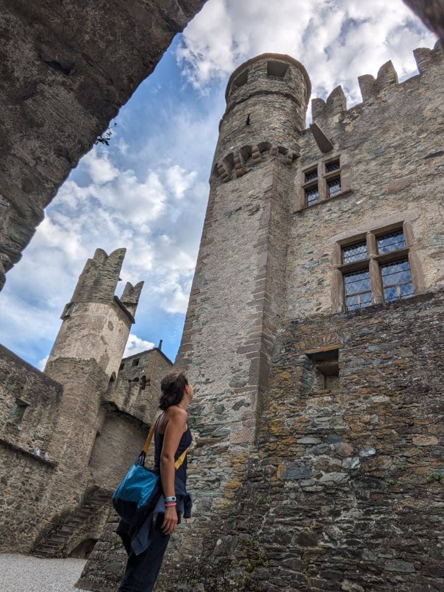 Linda betrachtet die Türme von Schloss Fénis, deren mittelalterliche Mauern in den Himmel ragen. Die Burg zählt zu den imposantesten historischen Bauwerken im Aostatal.