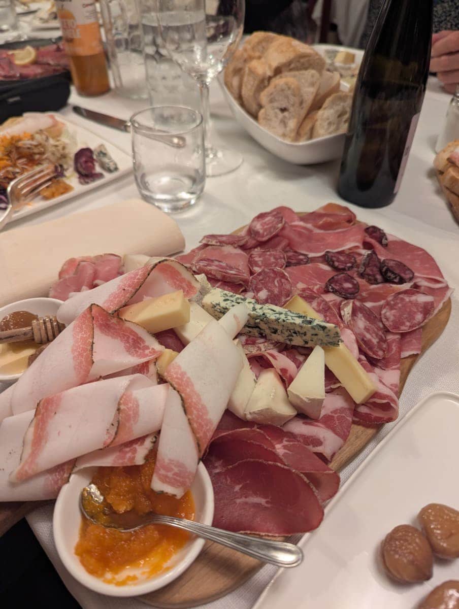 Eine regionale "Tagliere" mit Schinken, Speck, Salami, Käse und Aufstrichen wird in einem Restaurant serviert. Diese Spezialitätenplatte ist typisch für die kulinarische Vielfalt im Aostatal.