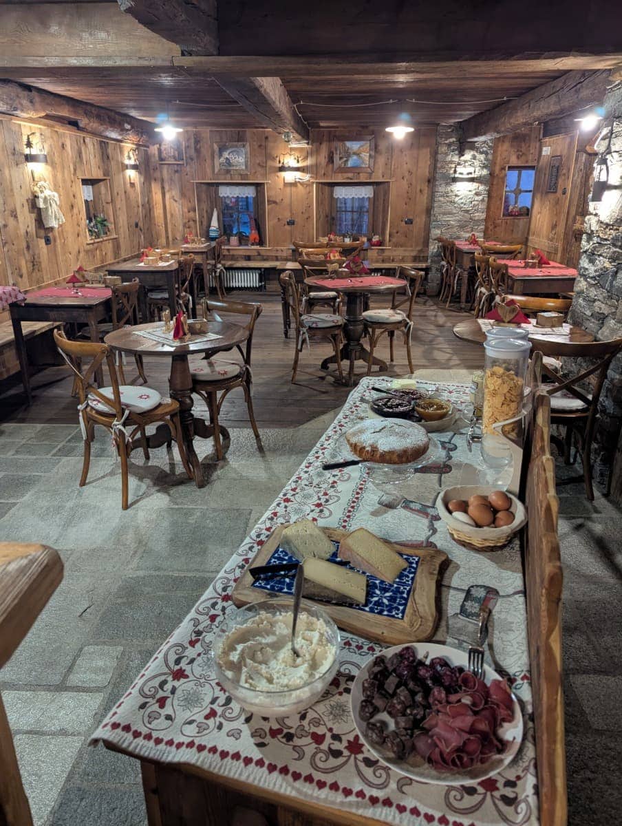 In einer gemütlichen Stube aus Holz ist ein Buffet mit Käse, Wurst und Kuchen aufgebaut. Die regionale Küche von Cogne im Aostatal.