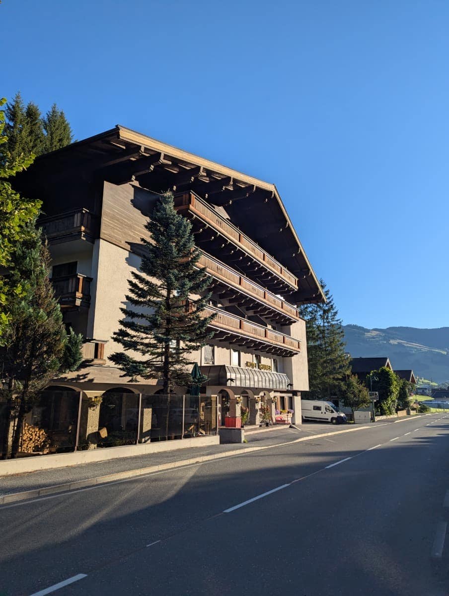 Außenansicht des Frosch Sportclub Thuiner in Saalbach Hinterglemm mit traditioneller Holzfassade und Balkonen. Von hier starten viele geführte Wanderungen in die Berge des Salzburger Lands.