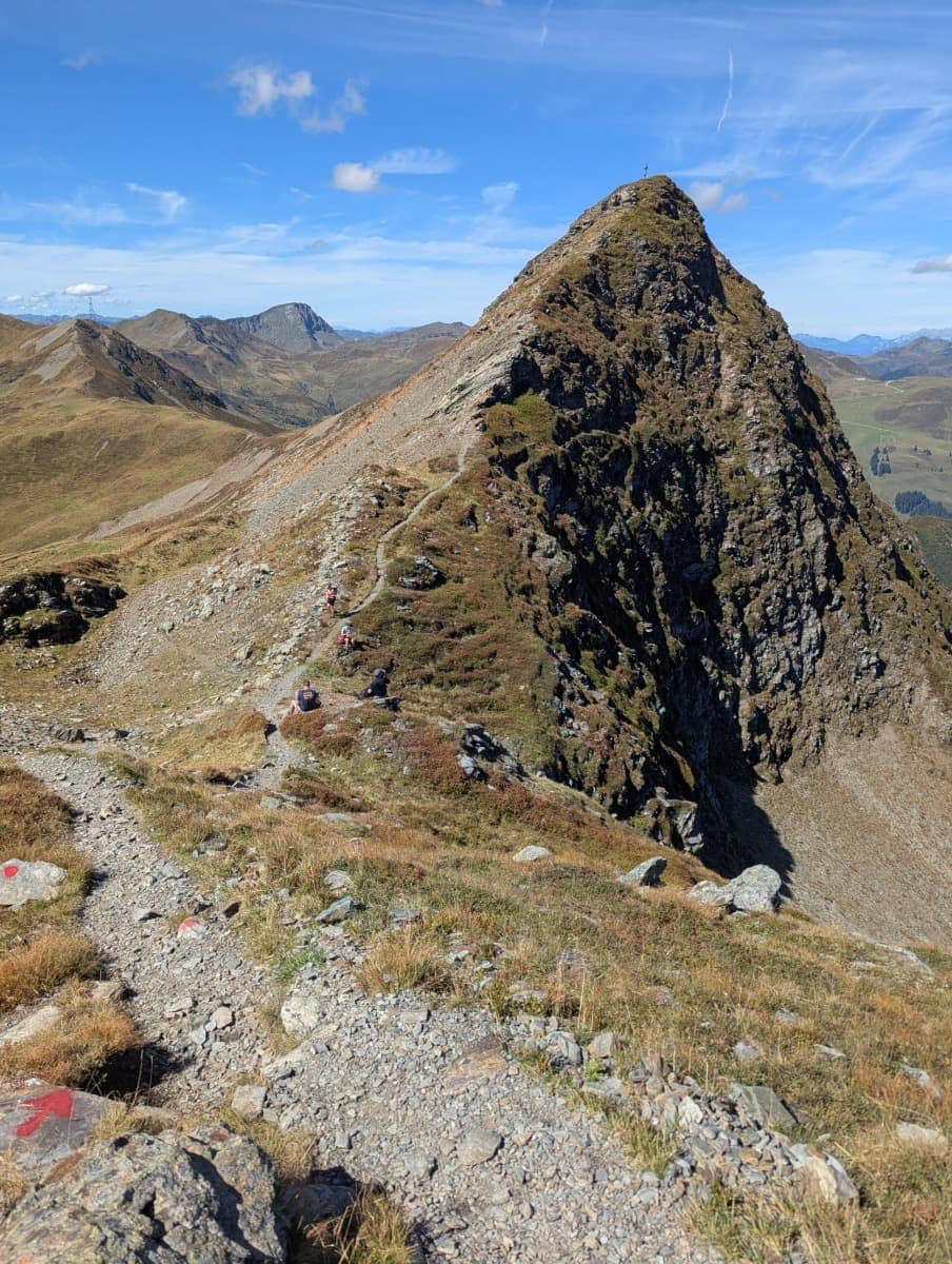 Ein schmaler Pfad führt hinauf zum markanten Gipfel mit Kreuz des Hochsaalbachkogel. Die anspruchsvolle Passage belohnt Wanderer mit spektakulären Ausblicken über Saalbach Hinterglemm.