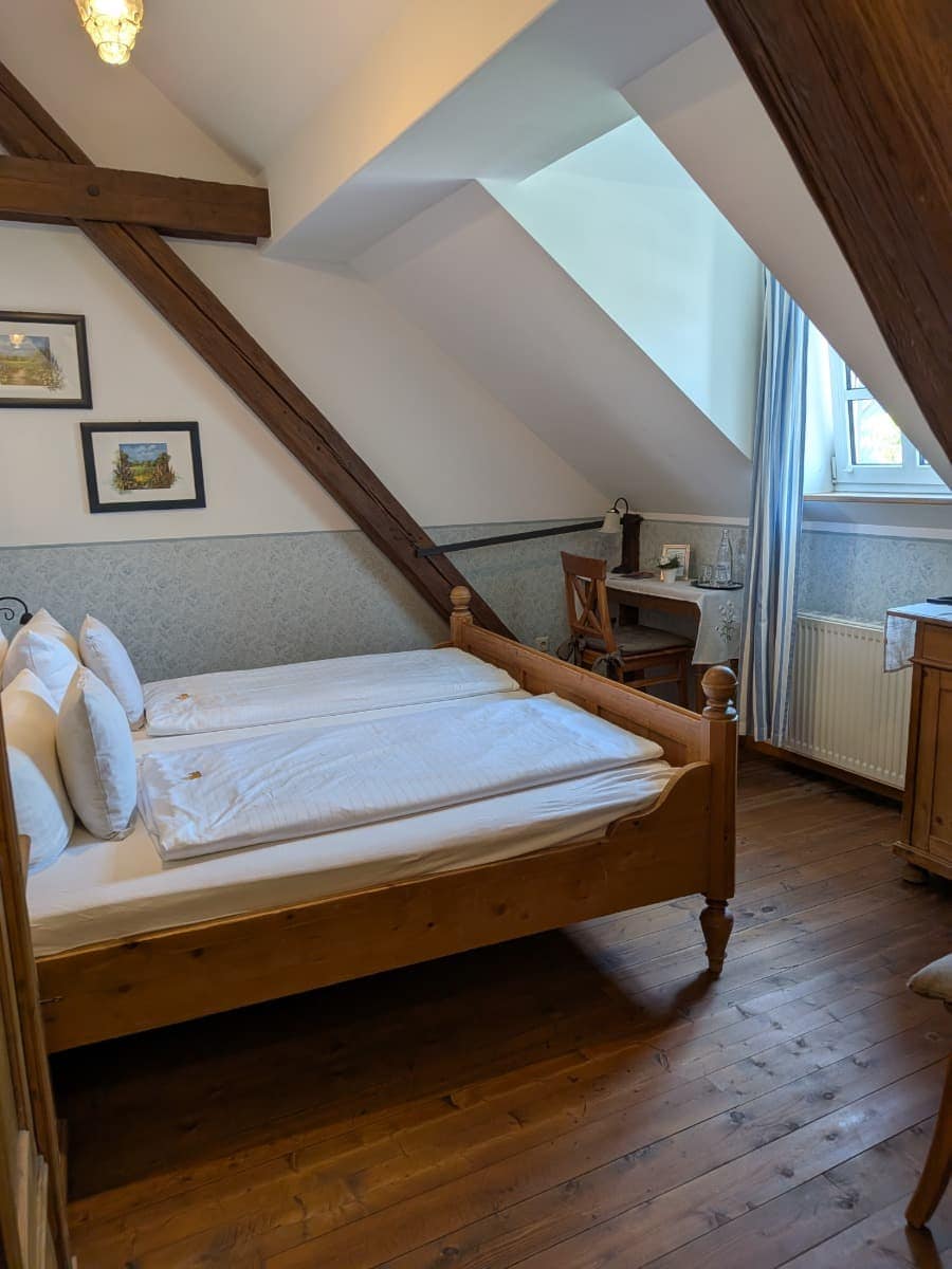 Rustikales Doppelzimmer im Hotel & Landgasthaus Altes Stadttor in Kastellaun mit Holzboden, sichtbaren Dachbalken und gemütlicher Einrichtung.
