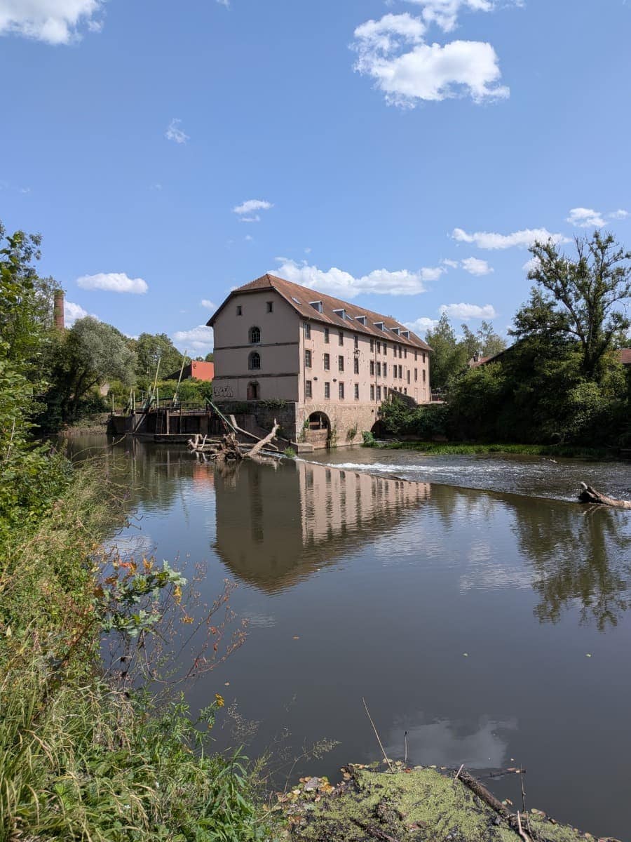 Die historische Bliesmühle spiegelt sich im ruhigen Wasser der Blies bei Sarreguemines und ist ein markanter Blickfang auf der ersten Etappe des Bliessteigs.