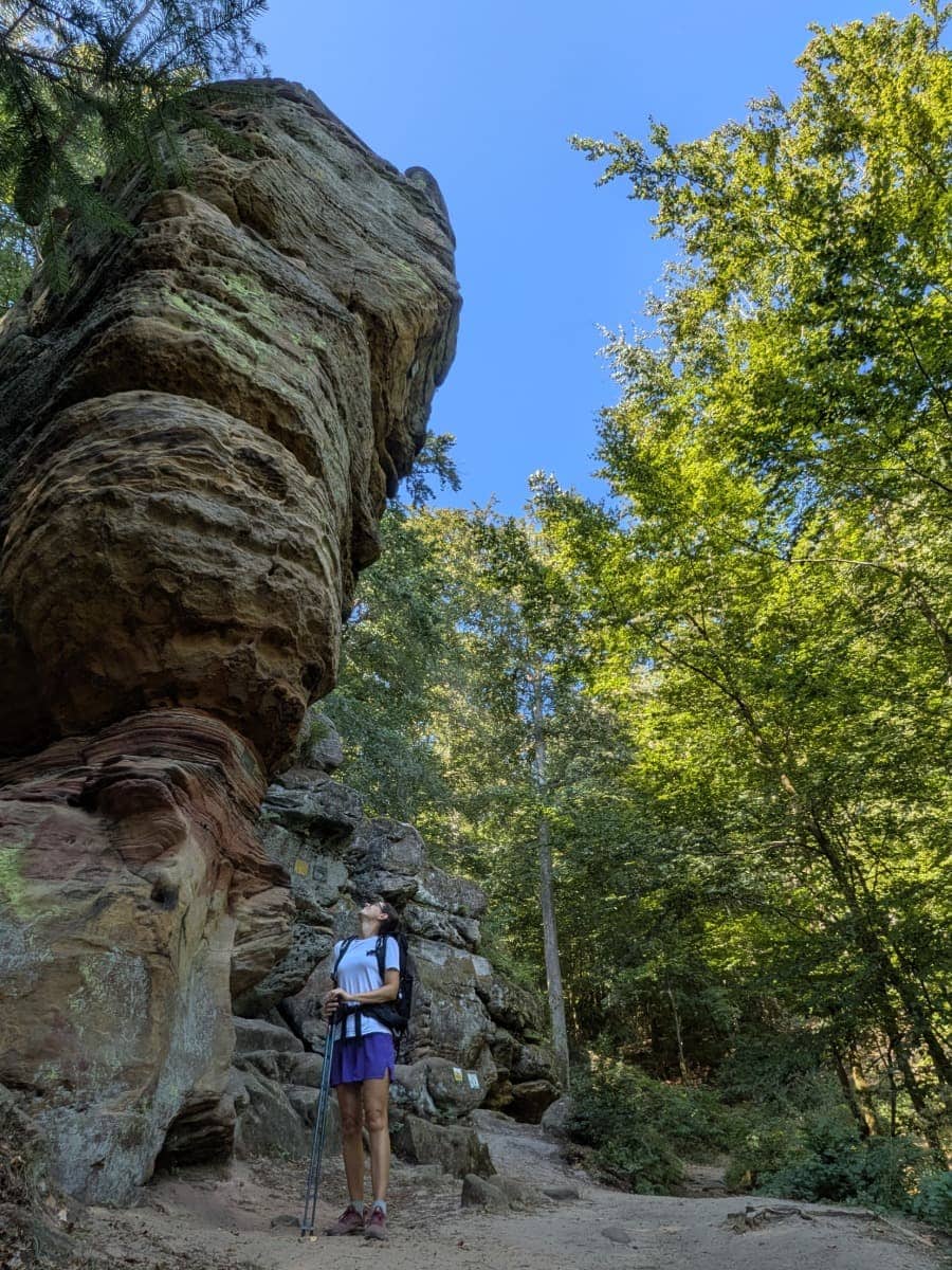 Linda steht unter einer mächtigen Buntsandsteinformation im Kirkeler Wald, einem landschaftlichen Höhepunkt auf dem Weitwanderweg Bliessteig zwischen Kirkel und Schwarzenacker im Saarland.