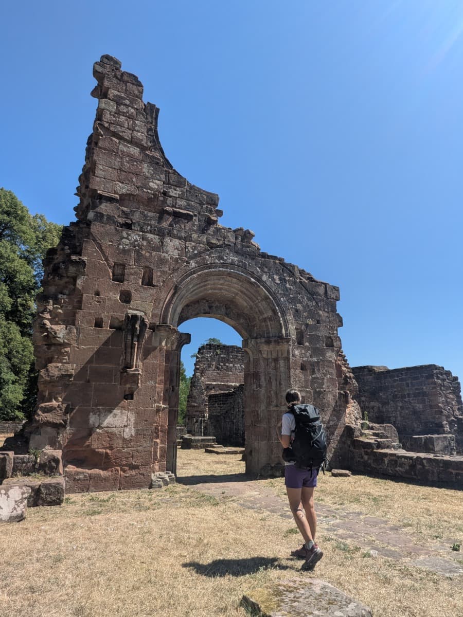 Linda geht durch den romanischen Torbogen der Klosterruine Wörschweiler, einem historischen Höhepunkt der fünften Etappe des Bliessteigs.