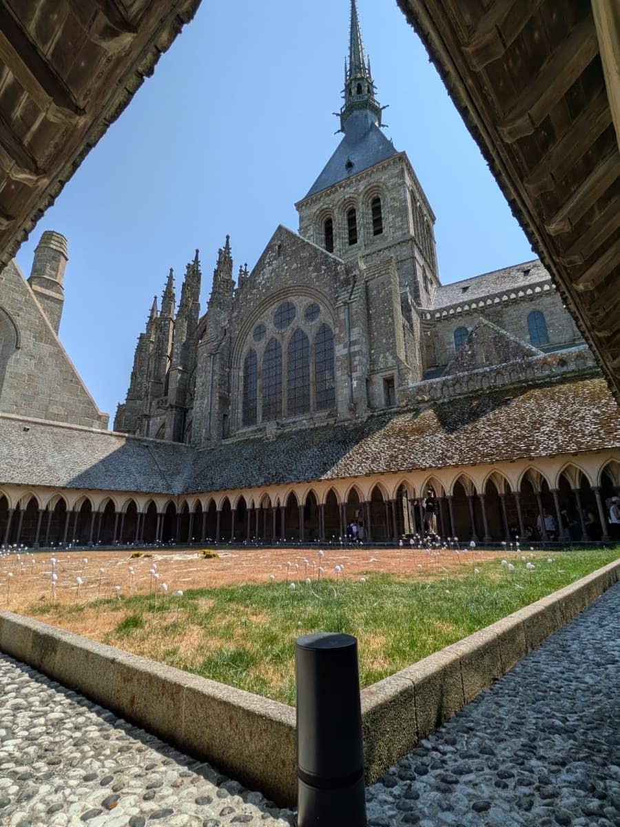 Der Kreuzgang der Abtei Mont Saint-Michel umschließt einen begrünten Innenhof unter den mächtigen Mauern des Klosters in der Normandie.