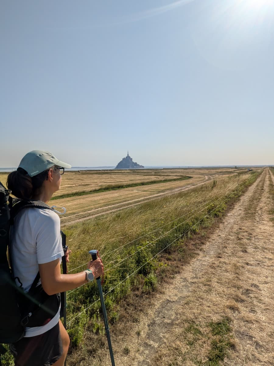 Linda blickt auf den Mont Saint-Michel, während sie über die weiten Salzwiesen auf den berühmten Klosterberg zuwandert.