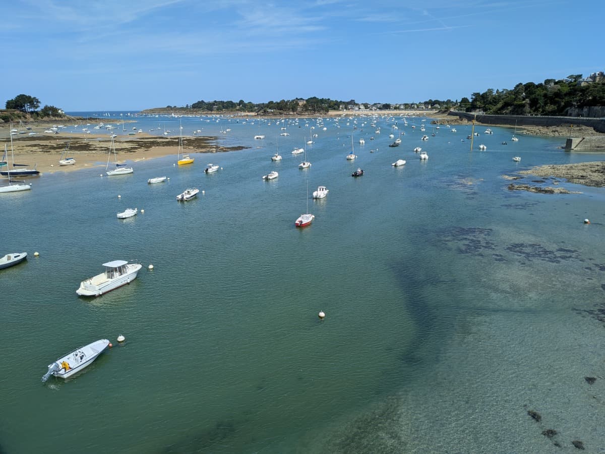 Zahlreiche Segel- und Motorboote liegen im türkisfarbenen Wasser der geschützten Bucht von Saint-Briac-sur-Mer an der bretonischen Küste entlang des Küstenwanderwegs GR34.