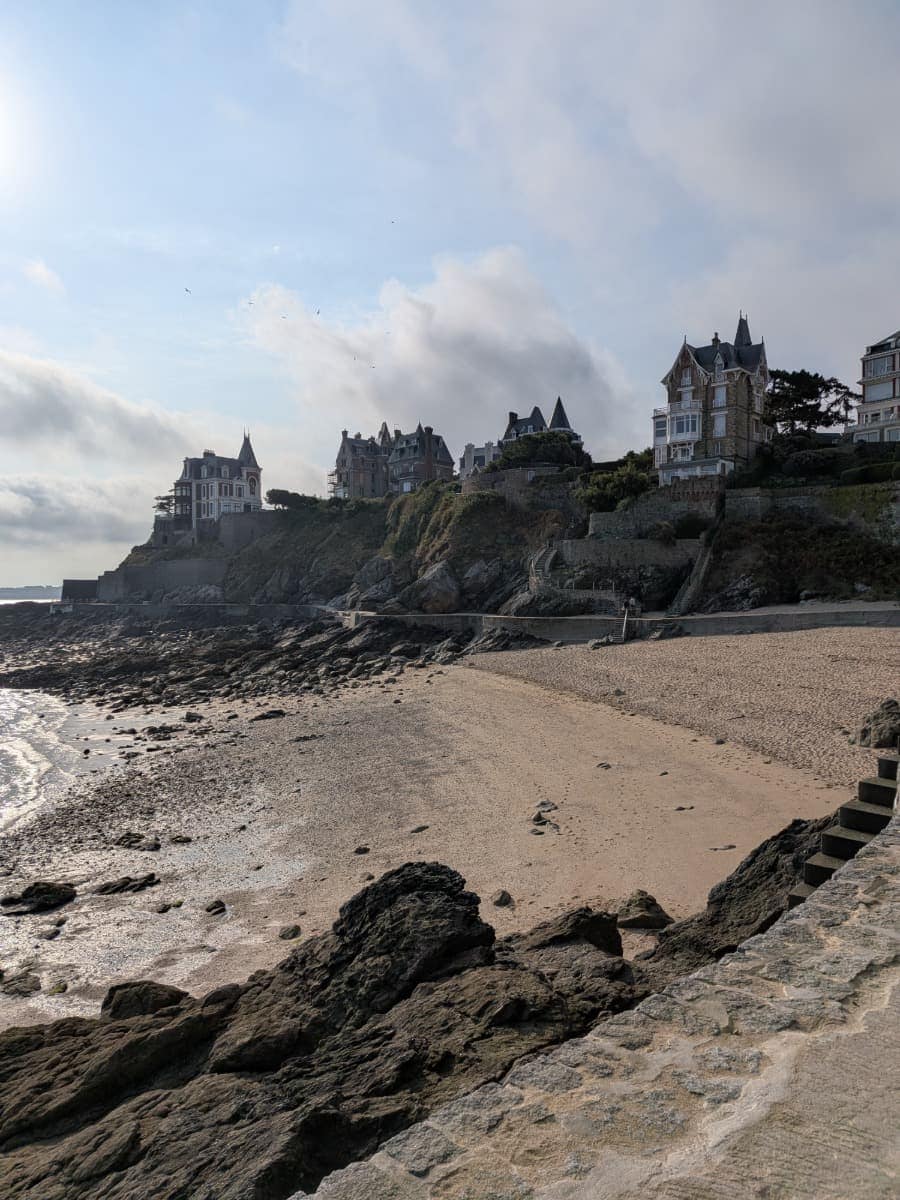 Historische Villen stehen über einem kleinen Sandstrand an der Smaragdküste und begleiten den Küstenwanderweg GR34 bei Dinard.
