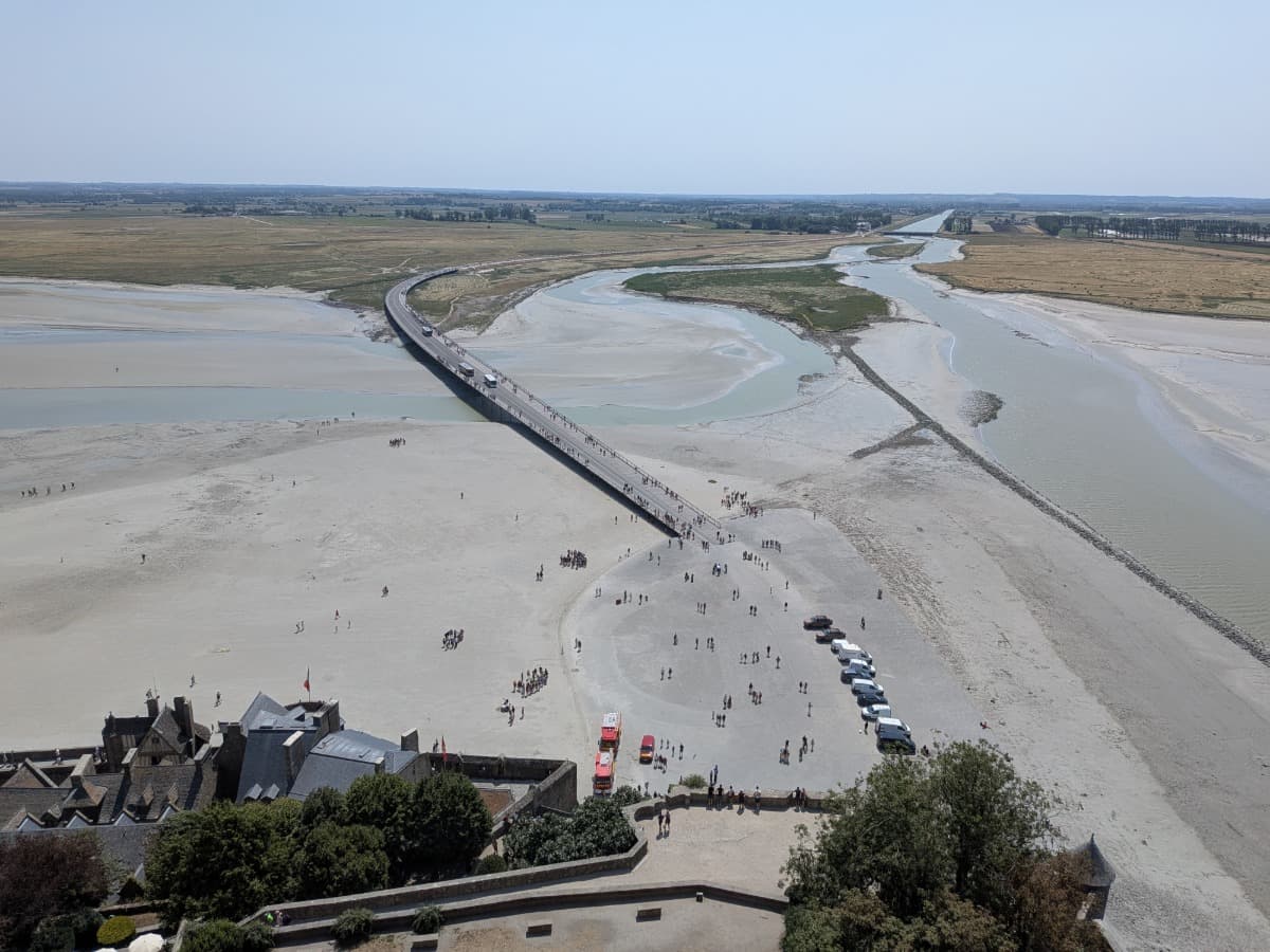 Aussicht von der Westterrasse der Abtei Mont-Saint-Michel auf den Passerelle du Mont-Saint-Michel, den Couesnon und das weitläufige Watt.