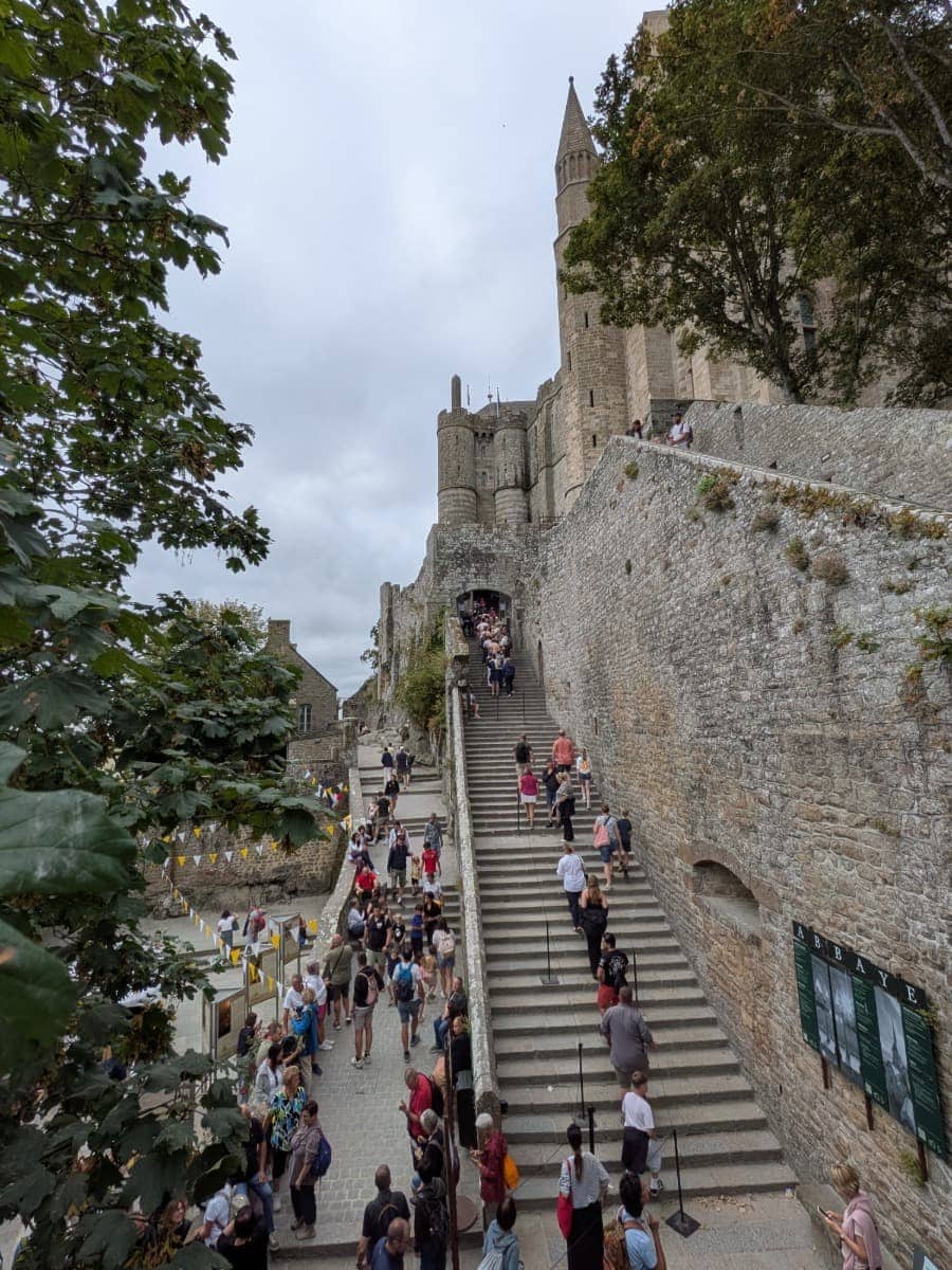 Besucher steigen über die Grand Degré hinauf zur Abtei Mont-Saint-Michel entlang der historischen Wehrmauern der Klosterinsel.