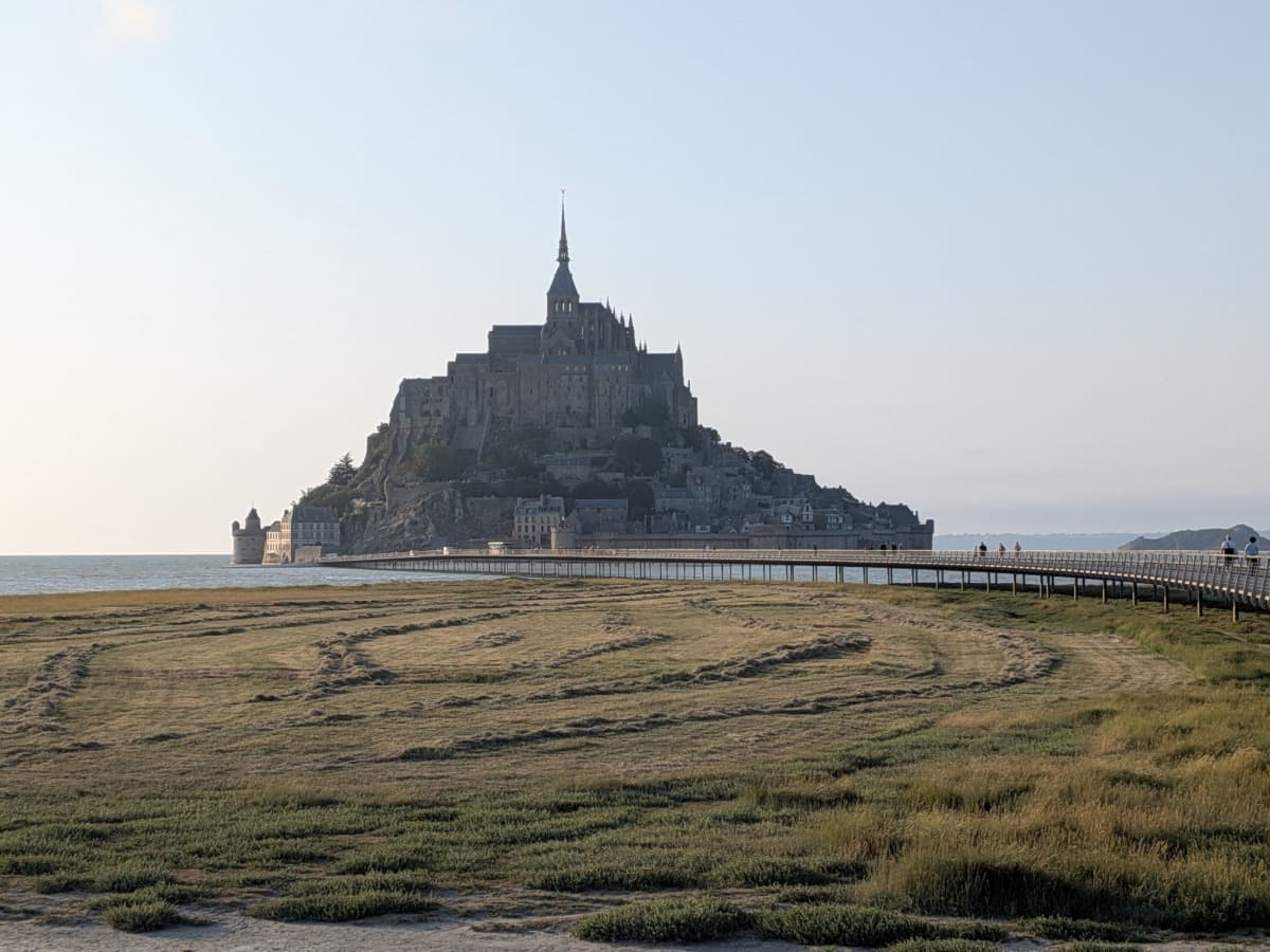 Der Mont-Saint-Michel erhebt sich über den Salzwiesen der Baie du Mont-Saint-Michel, während der Passerelle du Mont-Saint-Michel auf die berühmte Klosterinsel zuführt.