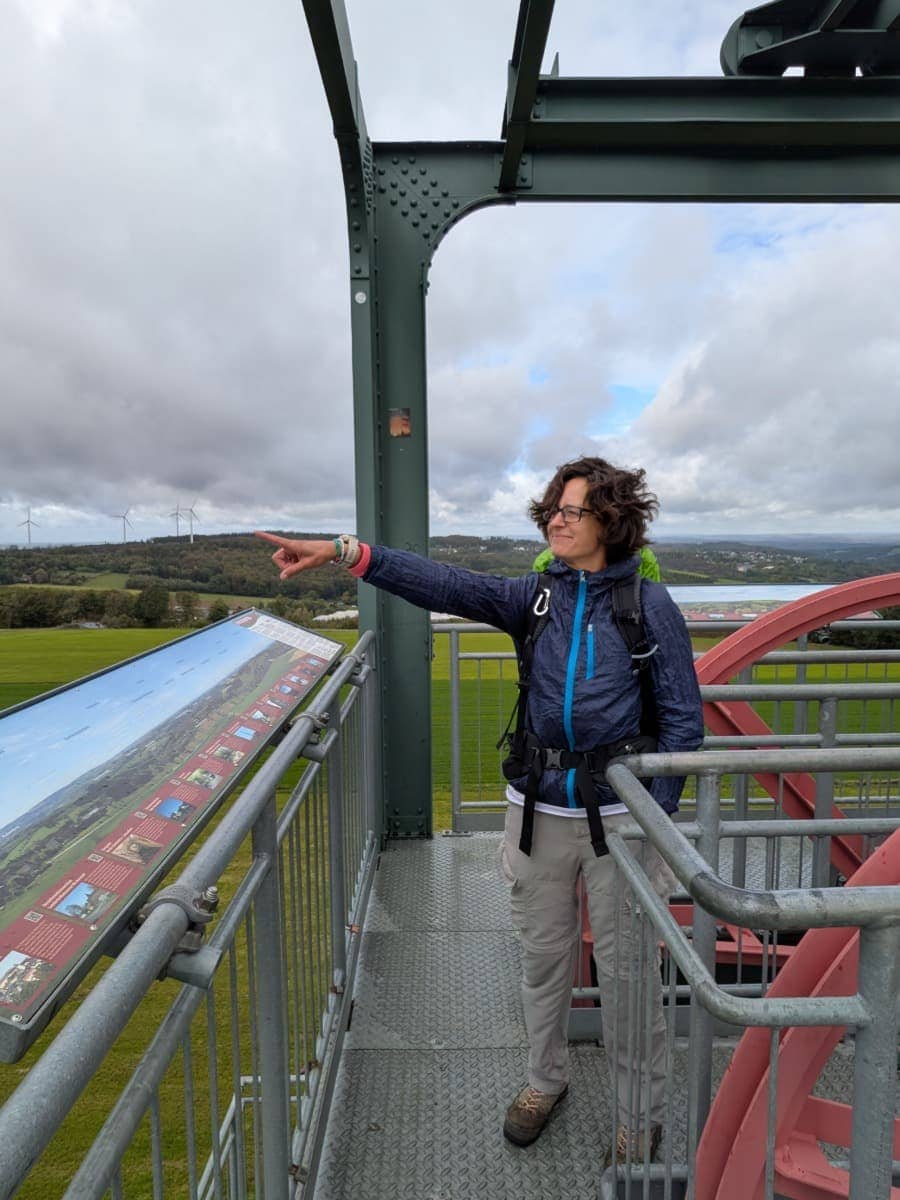 Linda zeigt von der Aussichtsplattform des Barbaraturms auf Windräder und bewaldete Hügel im Westerwald.