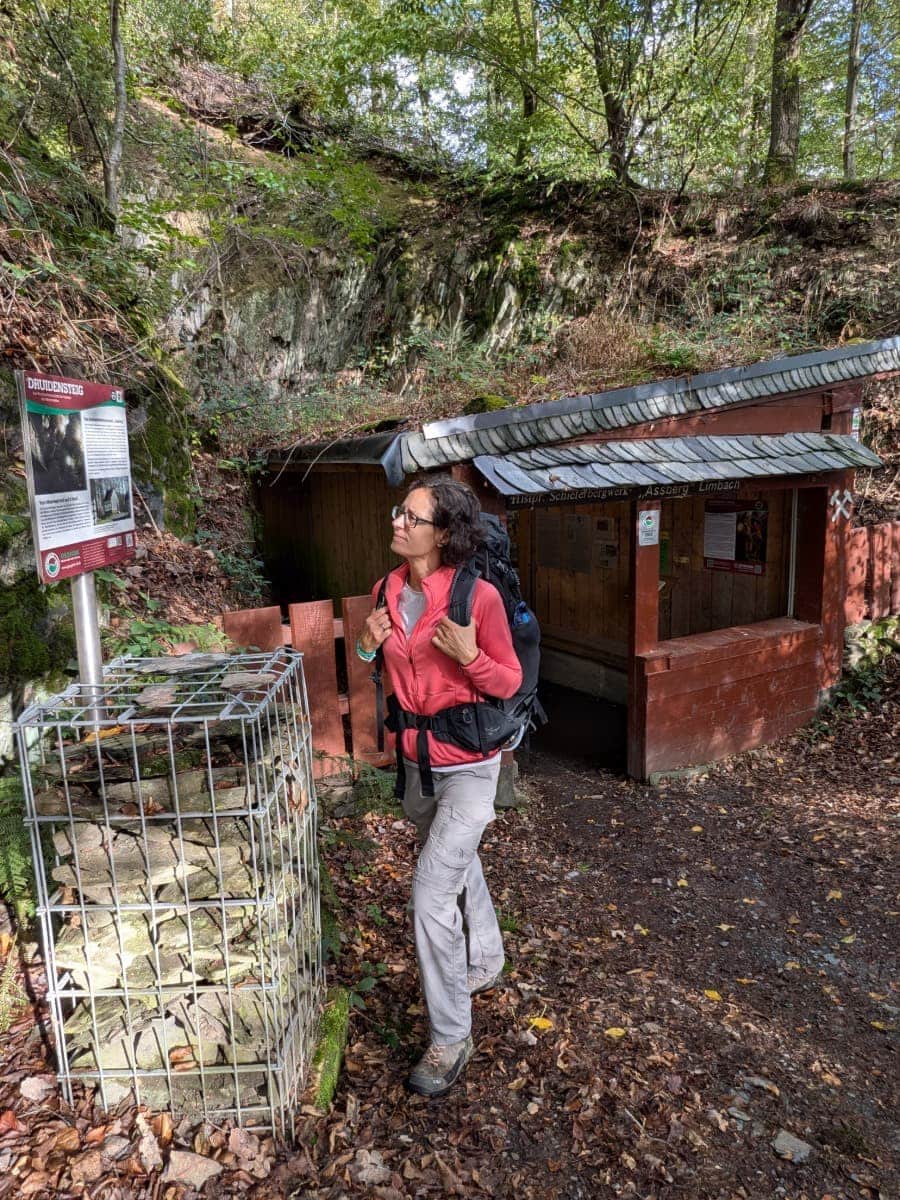 Linda steht vor dem Schieferbergwerk Assberg und betrachtet eine Infotafel über den Druidensteig.